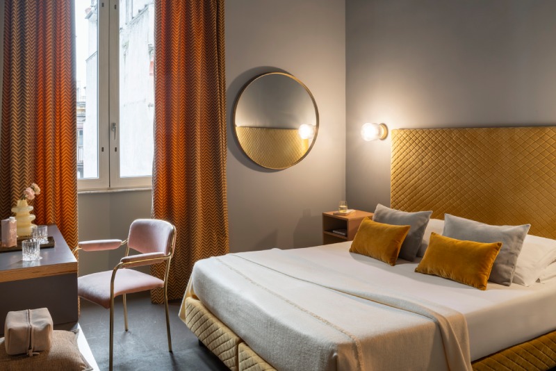 Master bedroom of the connecting Family Room featuring mustard headboard, ochre pillows and circular mirror - Hotel Milani, BZAR hotels in Rome