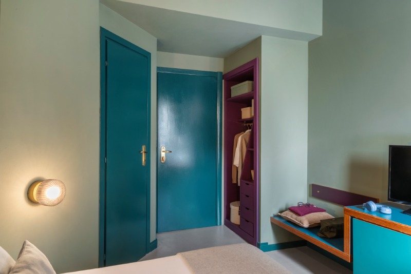 Small hotel room entrance detail with petrol blue doors and a purple open closet, optimizing space with contemporary design - Hotel Milani, BZAR hotels in Rome