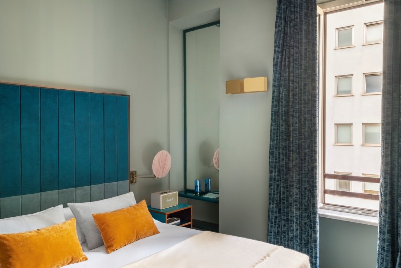 Standard room bed detail with blue velvet headboard, ochre pillows, vintage radio and textured curtains - Hotel Milani, BZAR hotels in Rome