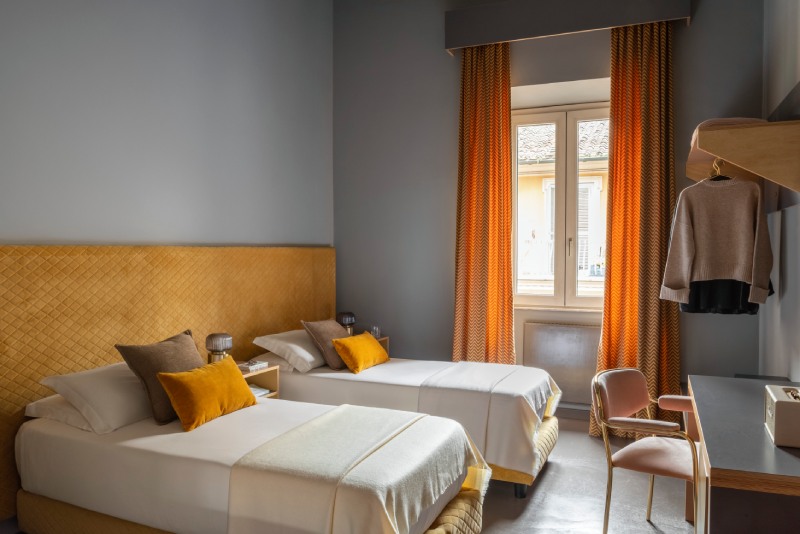 Standard twin room with two single beds, mustard tufted headboard and orange curtains against grey walls - Hotel Milani, BZAR hotels in Rome