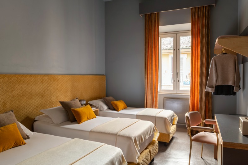 Triple room with three separate single beds, mustard headboard, and textured orange curtains - Hotel Milani, BZAR hotels in Rome